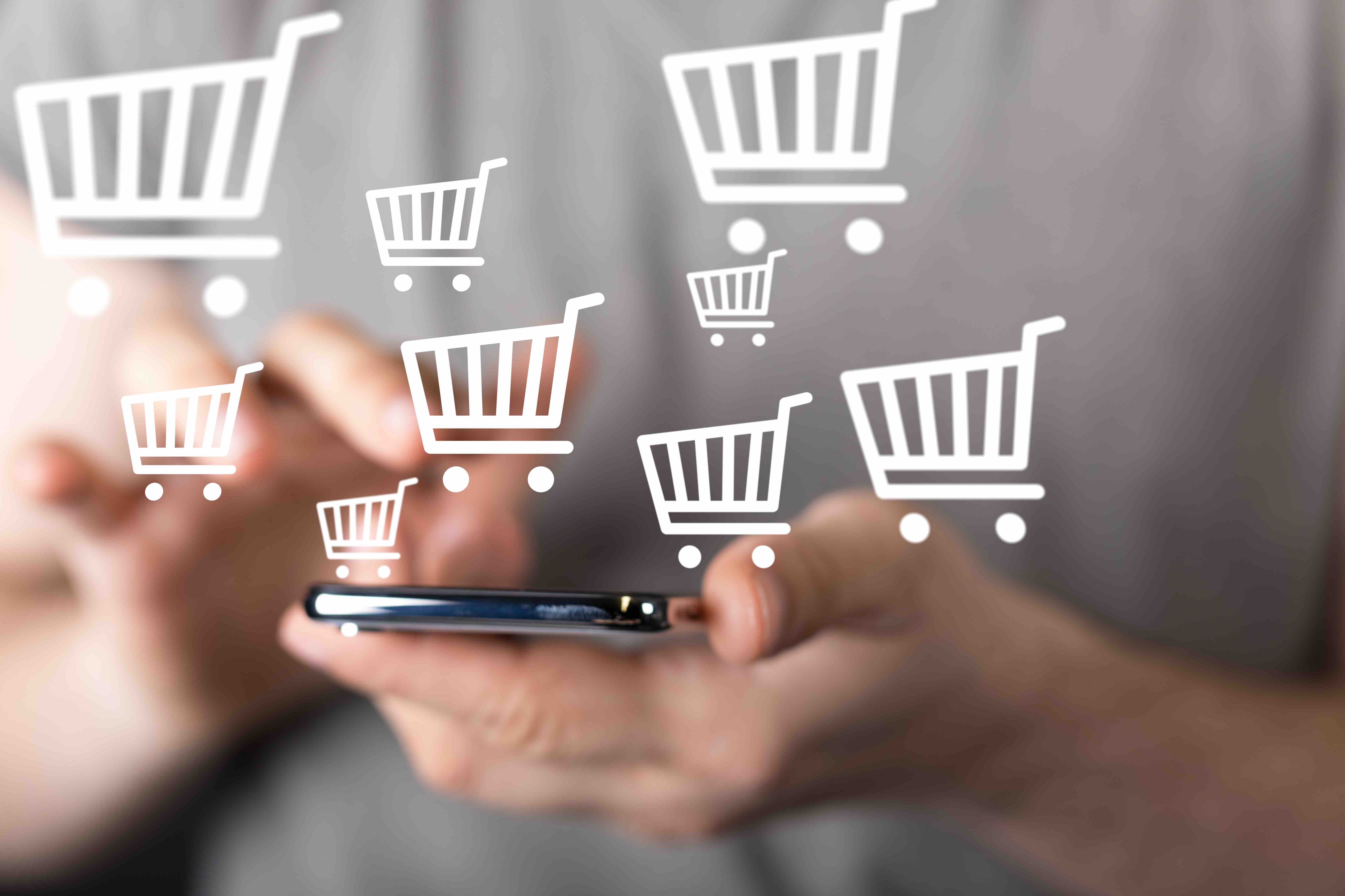 hand holding a phone with multiple ecommerce shopping cart icons floating