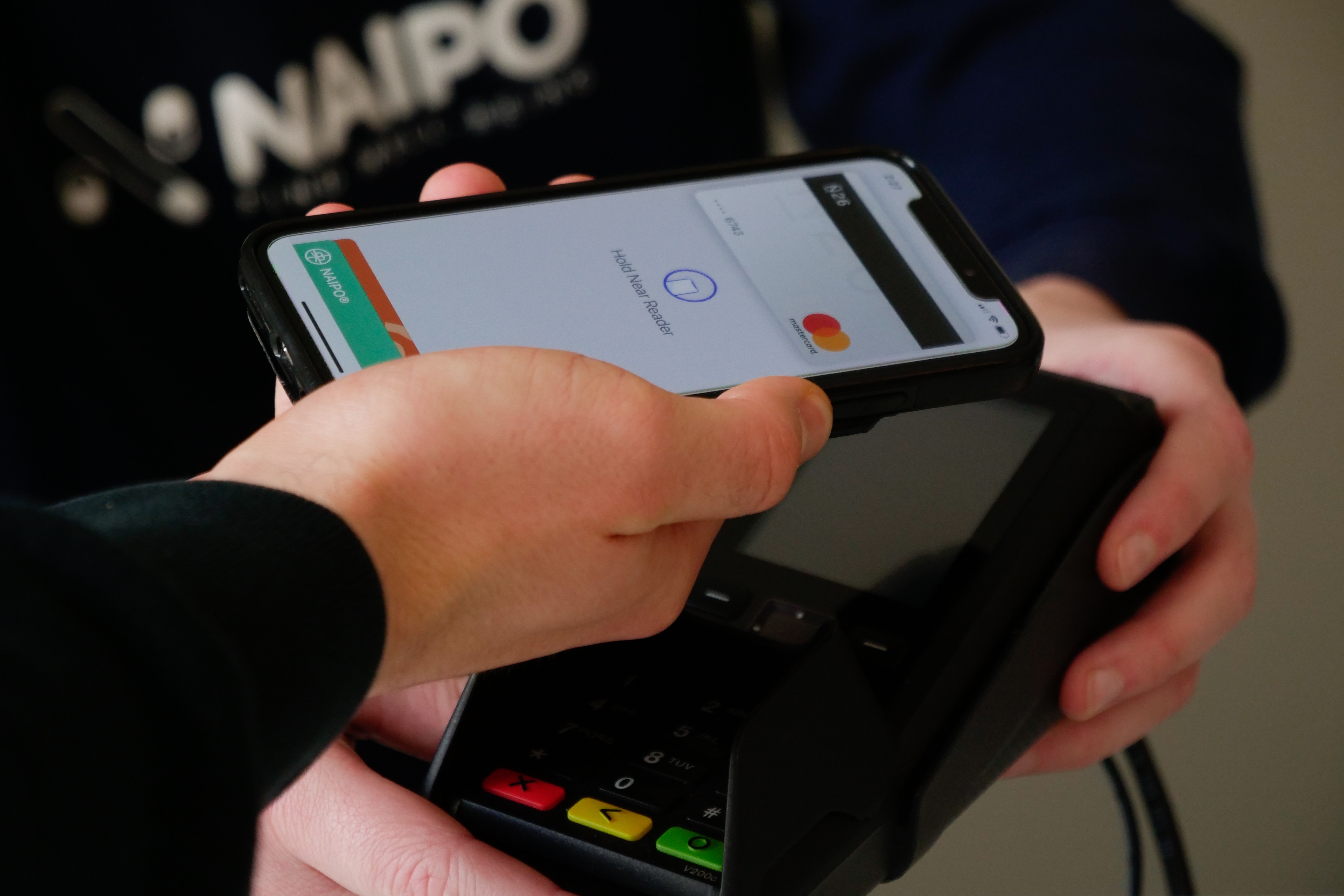 Man putting his phone near a POS system to pay for something